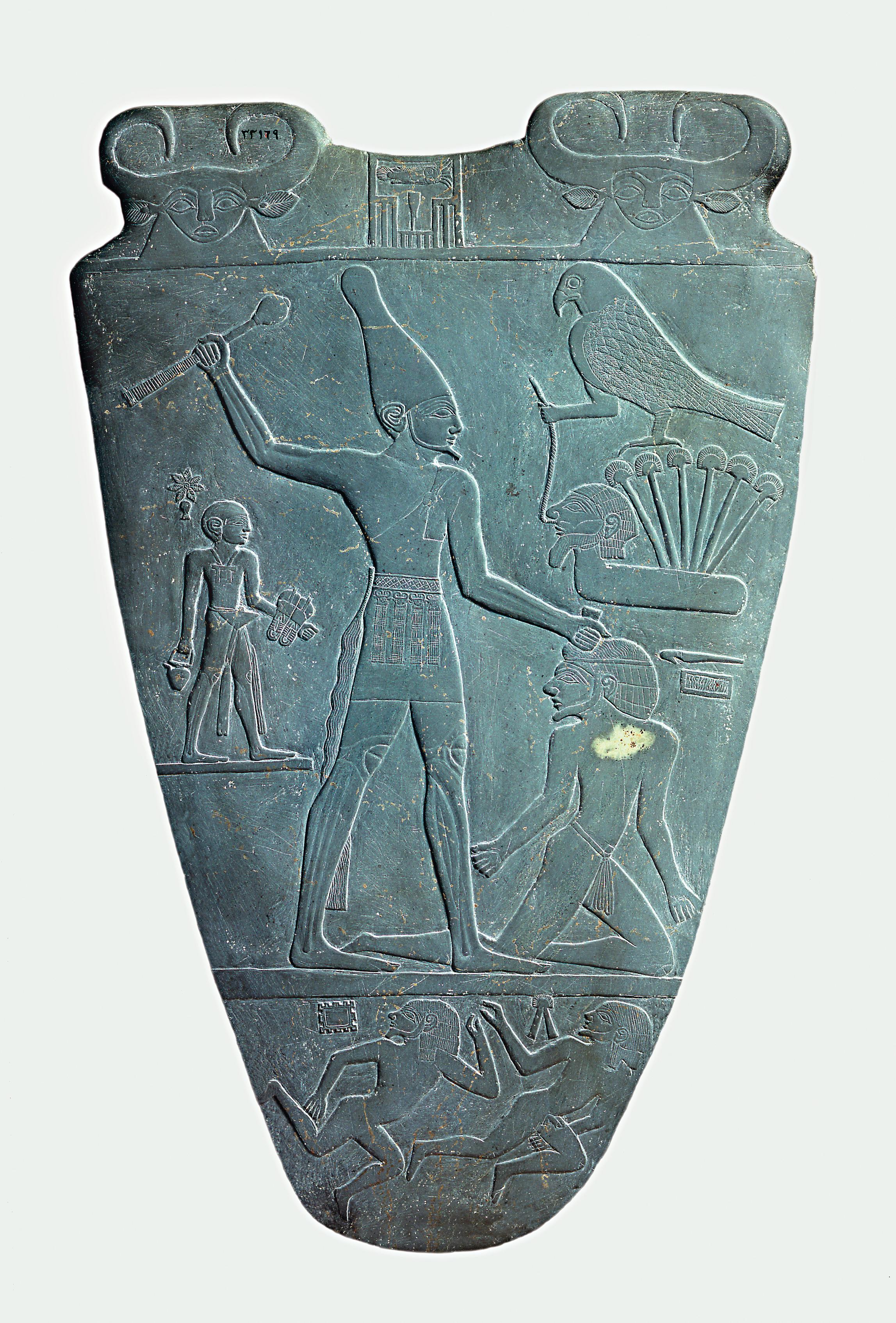 上图：主前31世纪的纳美尔石版（Narmer Palette）的正面，描绘统一了上下埃及的纳美尔头戴上埃及王冠，正要用权杖打破敌人的头，这个姿势后来成为埃及表现征服者的经典艺术形象。纳美尔石版是一个双面盾形的浮雕石板，一面描述戴着上埃及王冠的纳美尔，另一面描绘了戴着下埃及王冠的纳美尔，现藏于埃及开罗博物馆。